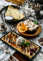 Assorted crepes or pancakes with greens, cheese, cherries, chocolate and meringue on rustic background. Healthy breakfast and lunch, top view