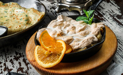 Meringue with slices of orange and mint on pan on rustic background. Sweets, dessert and pastry, top view