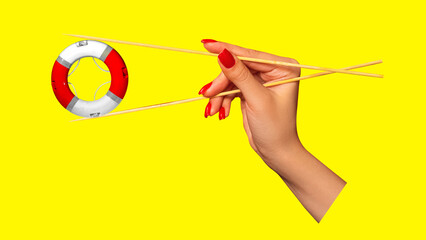 Hand with red nails delicately holding lifebuoy with chopsticks against bright yellow background....