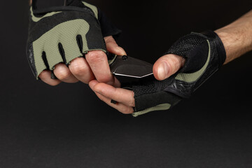 The man wearing tactical gloves using folding knife