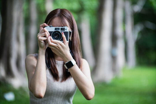young photographer holds vintage style film camera in her hand and inspects film camera for use after film cameras have become popular with photographers today because of their unique image tones.