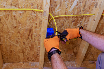 In electrician is installing assembled electrical wires on interior of residential construction site