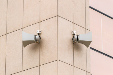 Two large speakers are mounted on a building. The speakers are white