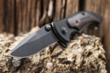 Tactical folding knife for survival on stone background