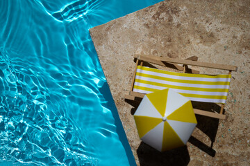 Summer Poolside Relaxation Scene. A bright yellow float and mini deck chair beside a pool with clear blue water