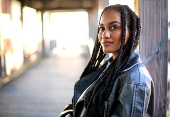 young black female with afro braids and beautiful features is staying on a wooden bridge with a...