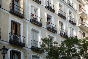 Classical facade of light colour with shuttered windows and tiny balconies downtown Madrid, Spain....