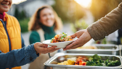 Volunteer hand extends food to homeless person, backlighting in warm tones, symbolizing charity and compassion
