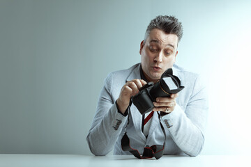 Man in gray suit inspects DSLR camera