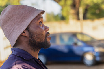 african american with profile view, with a beard wearing workwear outdoors, car in the background