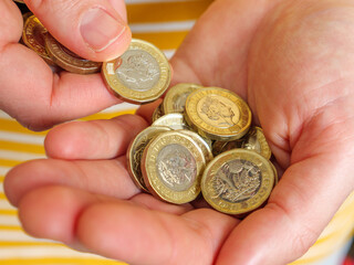 Close up of hands counting out cash money in UK 1 pound coins
