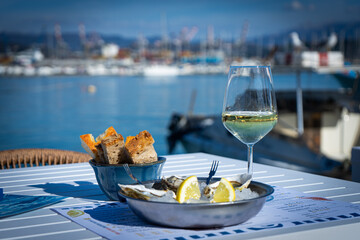 Piatto di ostriche e calice di vino bianco nel porto turistico di La Spezia, Liguria, Italia