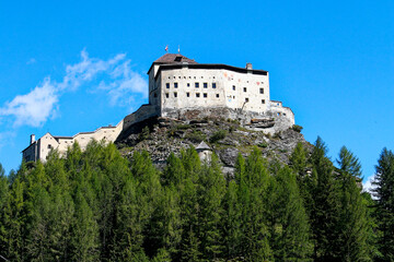 Naklejka premium Looking up Tarasp Castle on top of a rock on a sunny summer day in the Swiss Alps. Photo taken August 26th, 2006, Tarasp, Switzerland. 