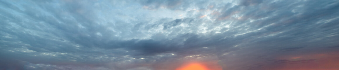 Real amazing panoramic sunrise or sunset sky with gentle colorful clouds. Long panorama.
