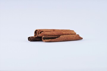 several pieces of cinnamon bark spice on a white table with studio lighting