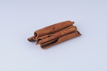 several pieces of cinnamon bark spice on a white table with studio lighting