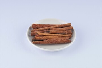 several pieces of cinnamon bark spice on a white table with studio lighting