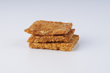 pieces of fried tempeh on a white plate on a white table with studio lighting