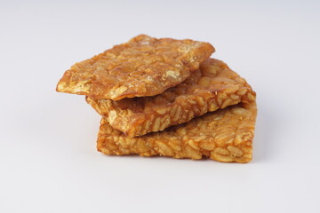 pieces of fried tempeh on a white plate on a white table with studio lighting