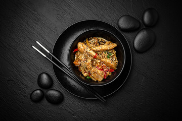 Wok noodles udon with chicken. Composition on black background. The Art of Japanese Cuisine. Food photography for menu and sushi bar decoration