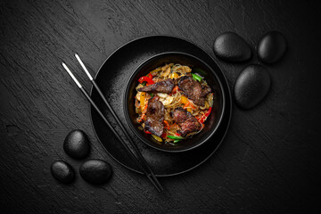Wok funchoza with beef. Composition on black background. The Art of Japanese Cuisine. Food photography for menu and sushi bar decoration
