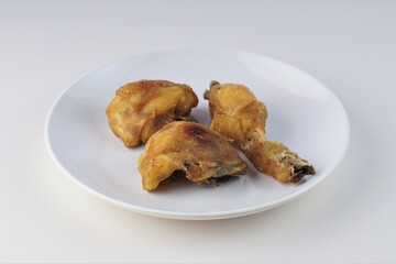 pieces of fried chicken on a white plate on a white table with studio lighting