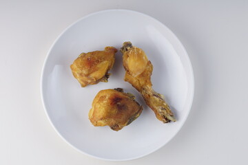 pieces of fried chicken on a white plate on a white table with studio lighting