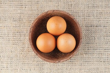 chicken eggs in a wooden bowl on a table with studio lighting