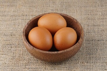 chicken eggs in a wooden bowl on a table with studio lighting