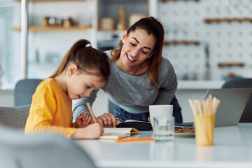 A loving mother gently guiding and helping her daughter through homework