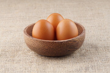 chicken eggs in a wooden bowl on a table with studio lighting