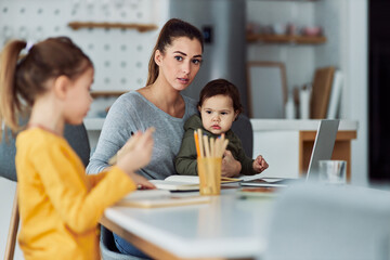 A worried single mother watching over her two children cautiously while working from home