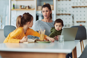 An irritated working mother scolding her daughter for being careless while trying to focus on work