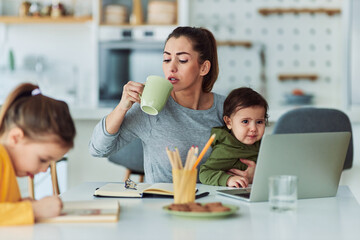 A hard-working mother taking care of her children while working from home and having a cup of coffee