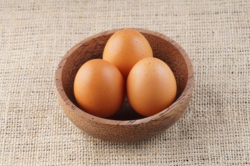 chicken eggs in a wooden bowl on a table with studio lighting
