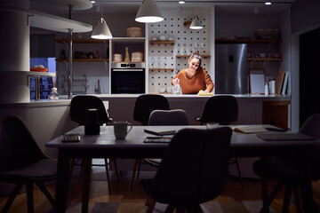 A diligent young adult housewife staying up late at night and cleaning the kitchen counter in her apartment