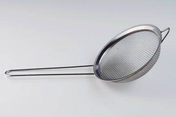stainless food strainer over white background with studio lighting