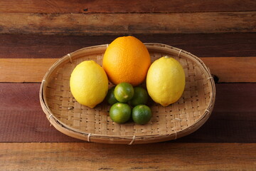 various types of oranges on a woven bamboo plate on a wooden background with studio lighting