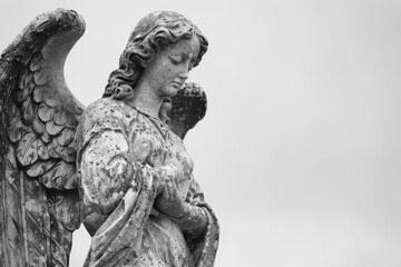 Monochrome photo capturing a sorrowful angel statue, symbolizing mourning and remembrance in a peaceful funeral or condolence setting