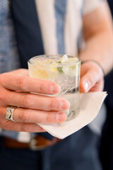 A man is holding a lime gin cocktail at an event. 