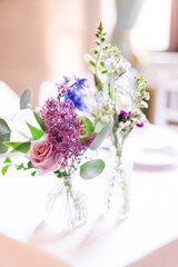 Simple wildflower and roses in vases on a white tablecloth table 