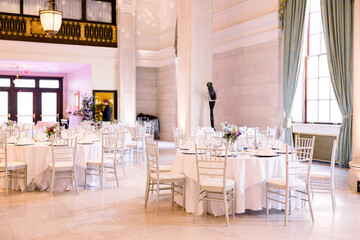 An elegant ballroom with white tablecloth tables and chairs set up for a wedding reception