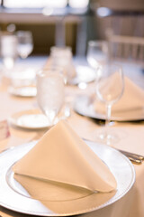 Folded napkins on silver chargers on a table set up for an event 