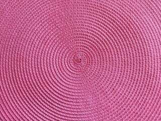 Beautiful background backdrop of concentric circles in pink lilac corals color. Wicker plastic texture. Circle pattern on a plastic napkin.