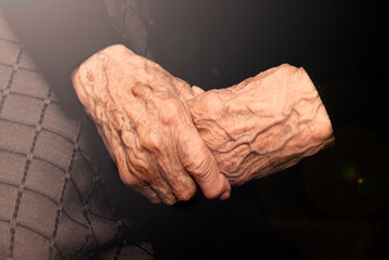 Closeup of the philosophical view of the crossed elderly hands of a centenarian grandmother with...