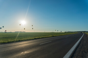 hot air balloon flying over the road
