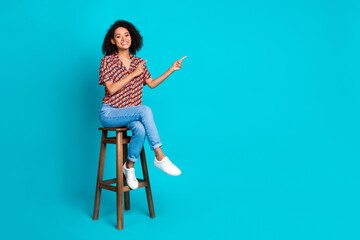Photo of positive girl sit bar stool pointing empty space isolated cyan color background