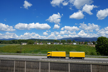 yellow lorry with trailer passes Deggendorf on the A3 motorway, background Bavarian Forest, Lower...