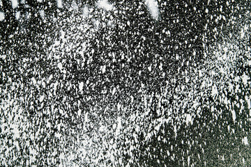 A black and white photo of snowflakes falling on a dark background
