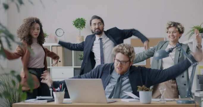 Diverse group of businesspeople dancing in modern office looking at computer screen enjoying successful partnership. Business and fun concept.